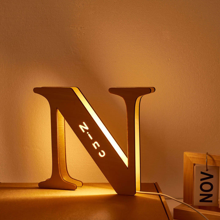Illuminated wooden letter N lamp casting a warm glow, personalized Enchanted Woodland Alphabet Lamp for nurseries and bedrooms.