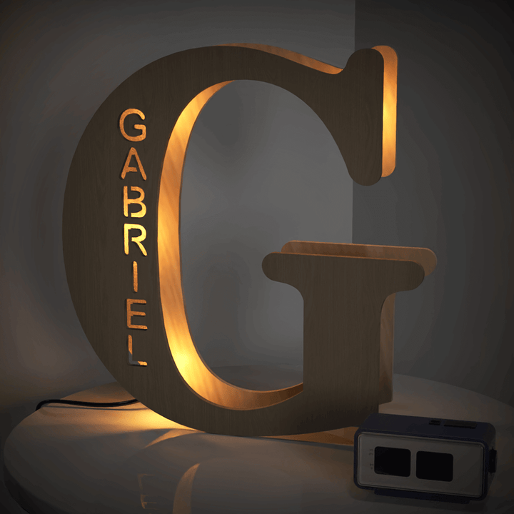 Illuminated wooden 'G' letter lamp with personalized name 'Gabriel' on a tabletop, part of the Enchanted Woodland Alphabet Lamp collection.