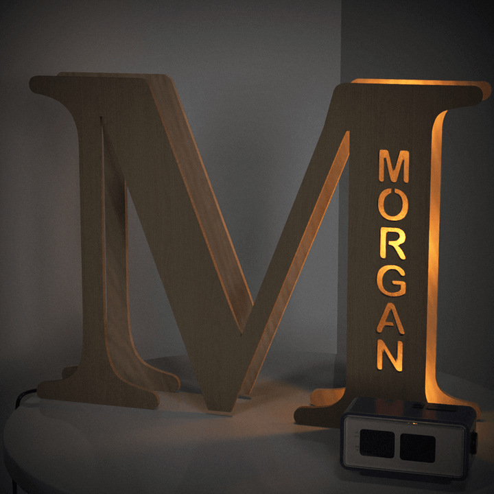 Wooden letter 'M' illuminated lamp with the name 'Morgan' cutout, glowing warm light in a cozy room setting