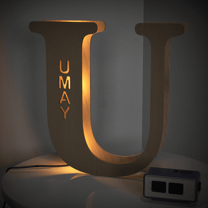 Illuminated Enchanted Woodland Alphabet Lamp letter U on a table, personalized with the name UMAY, glowing warmly in a dark room.