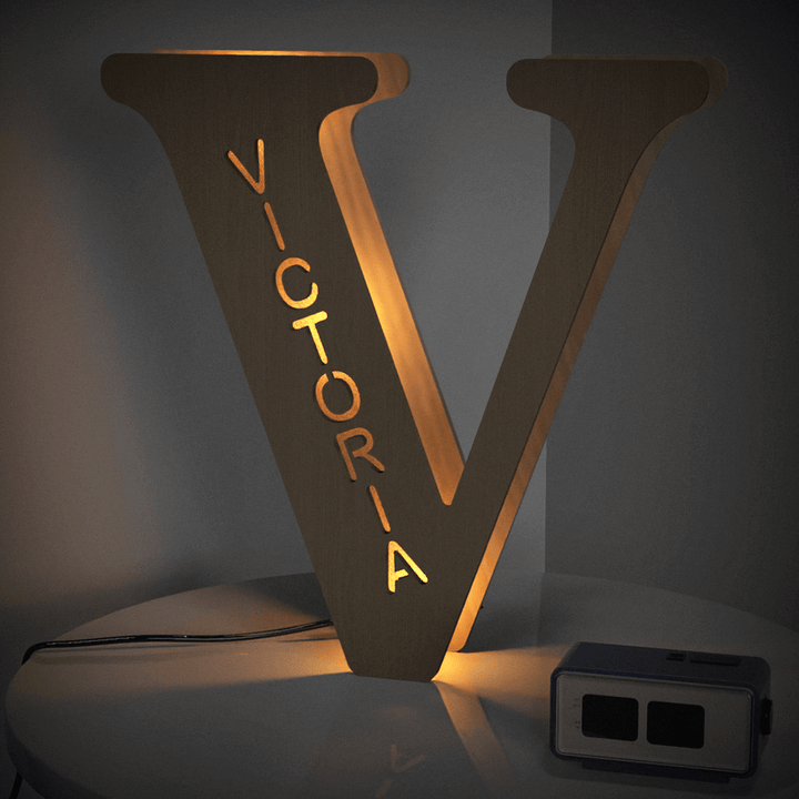 Illuminated wooden letter V with the name Victoria, part of Enchanted Woodland Alphabet Lamp collection, casting a warm glow.