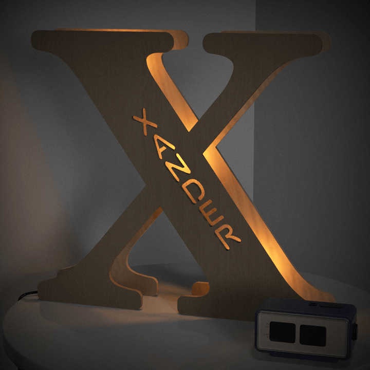 Wooden Alphabet Lamp in the shape of X illuminated with warm glow on a side table